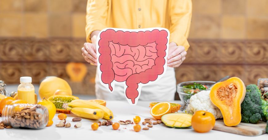 Immagine di un colon sano su un tavolo con alimenti consigliati per il colon irritabile, come frutta e verdure fresche