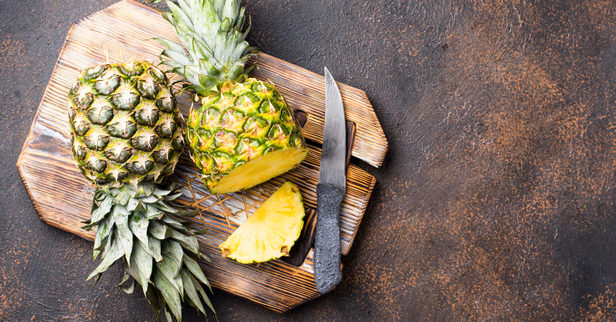 Ananas tagliato su tagliere di legno con coltello, ottima fonte di bromelina per supportare la digestione ma sconsigiato in caso di colite