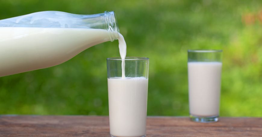 Latte versato alcuni bicchieri su un tavolo, un alimento da evitare per le persone con colite e colon irritabile